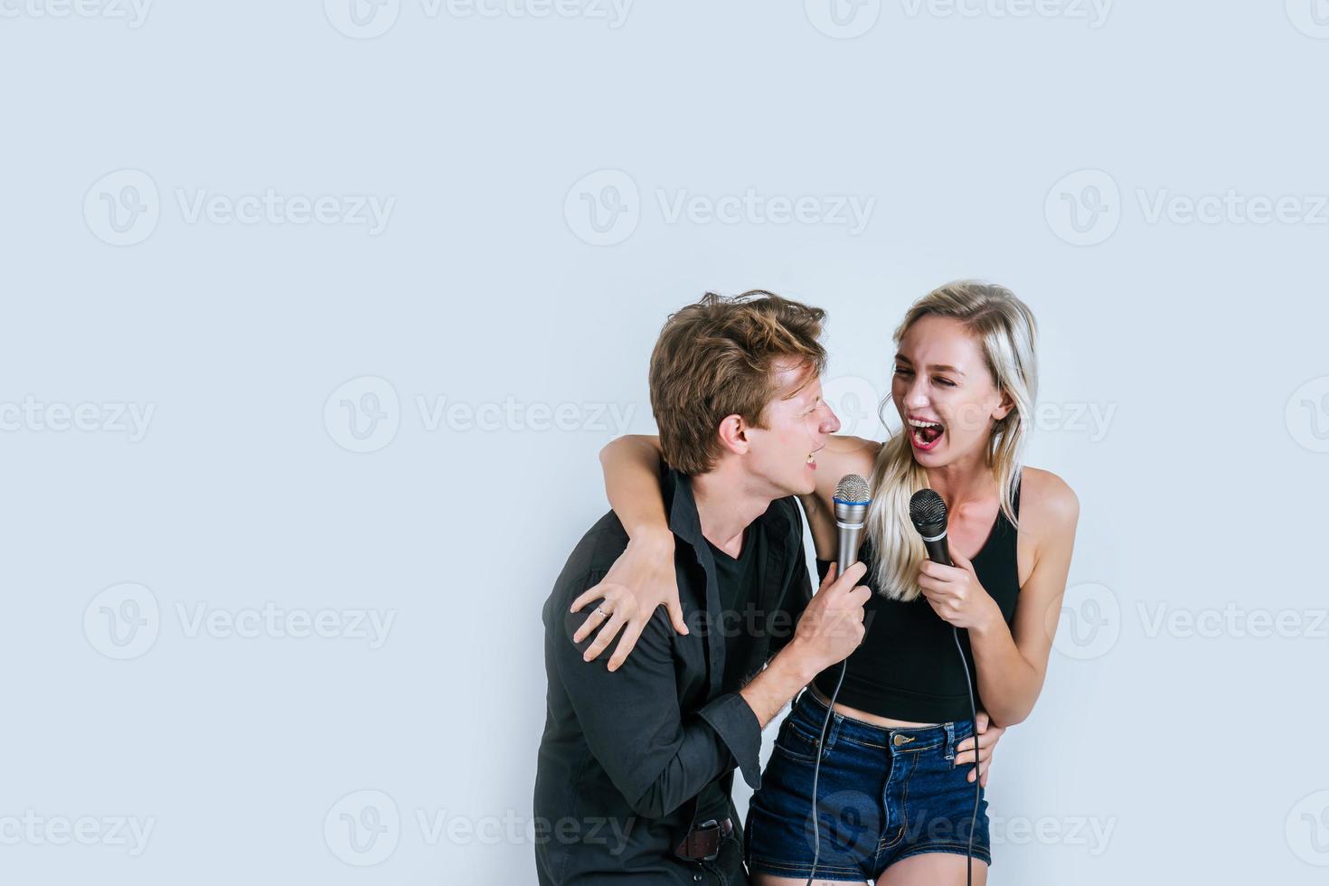 feliz retrato de pareja sosteniendo micrófonos y cantando foto