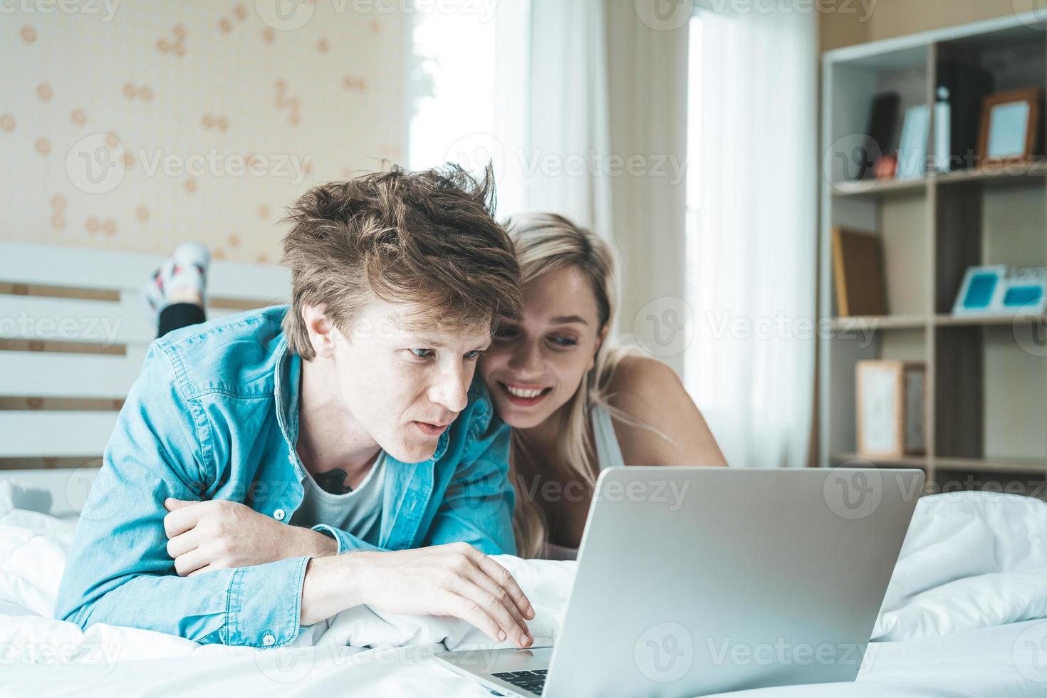Happy couple using laptop computer on the bed photo