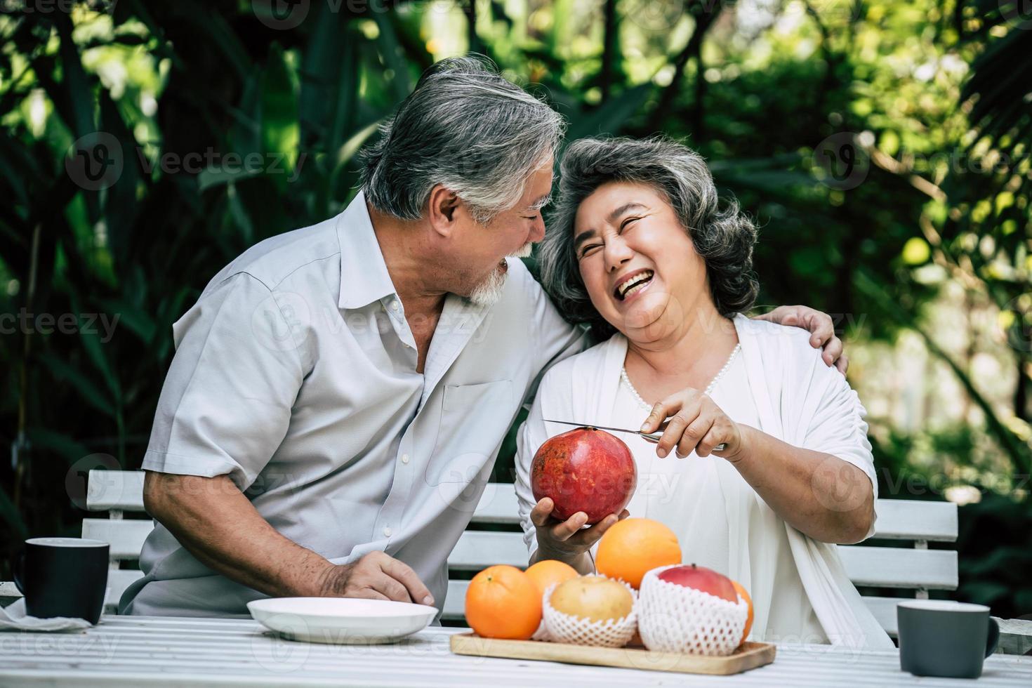 pareja de ancianos cortando y comiendo fruta foto