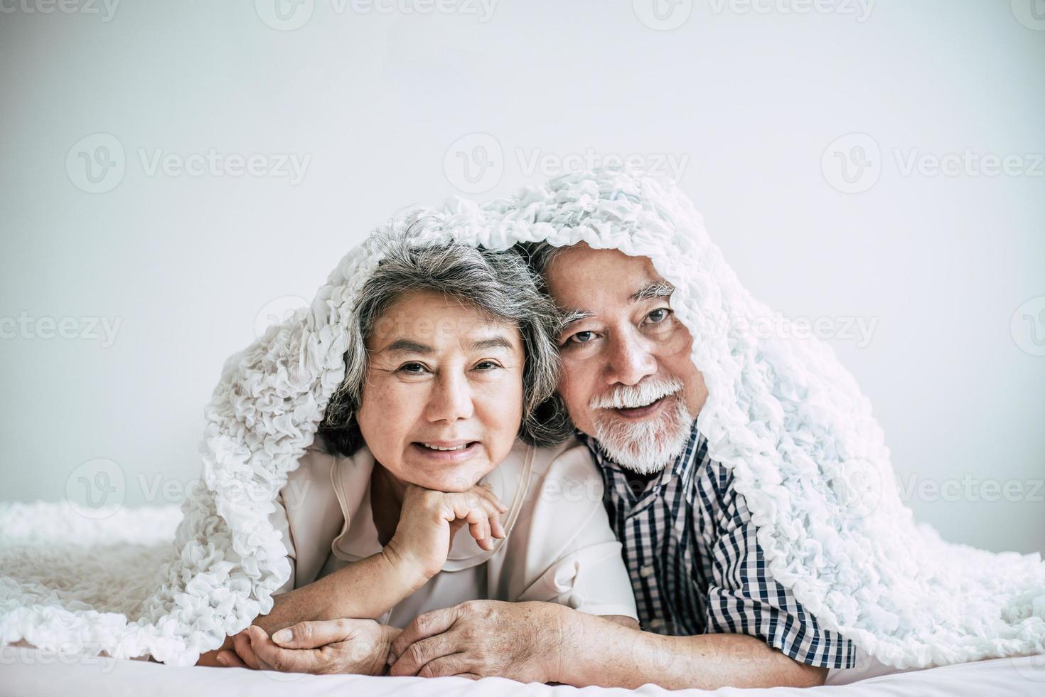 Happy senior couple laughing in bedroom photo