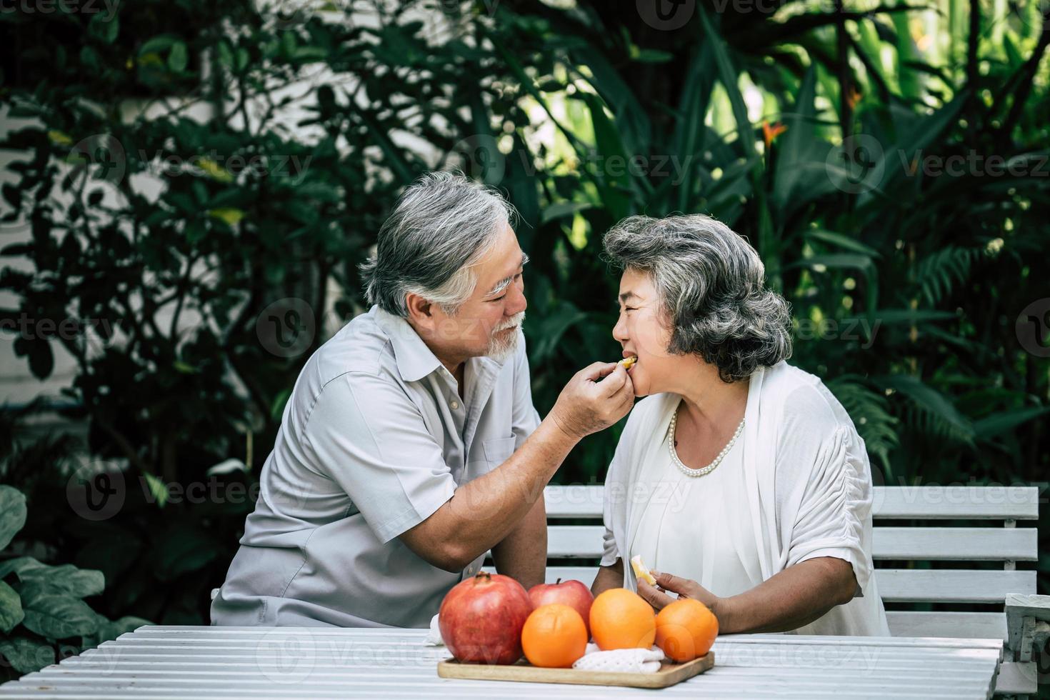 pareja de ancianos jugando y comiendo fruta foto
