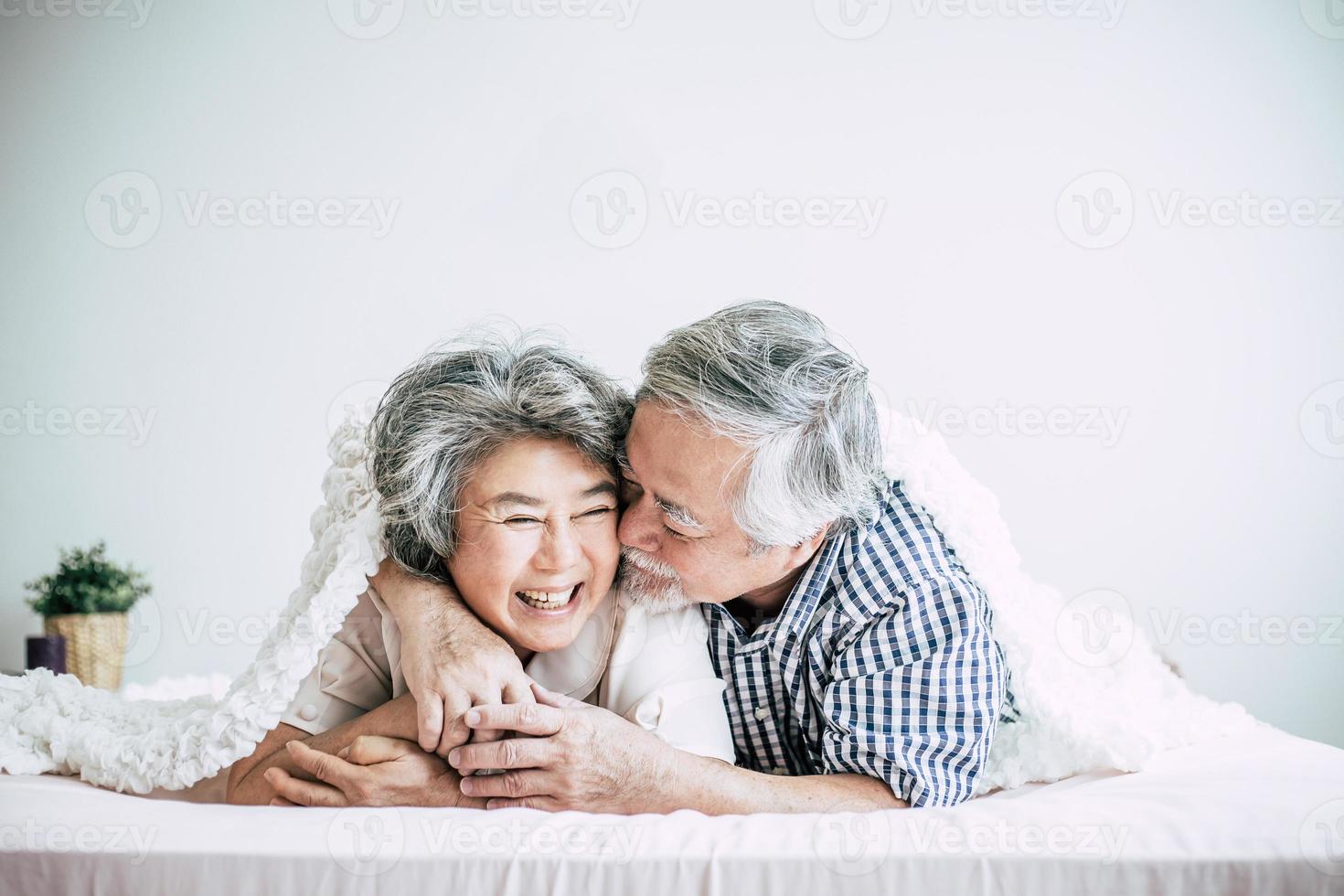 Happy senior couple laughing in bedroom photo