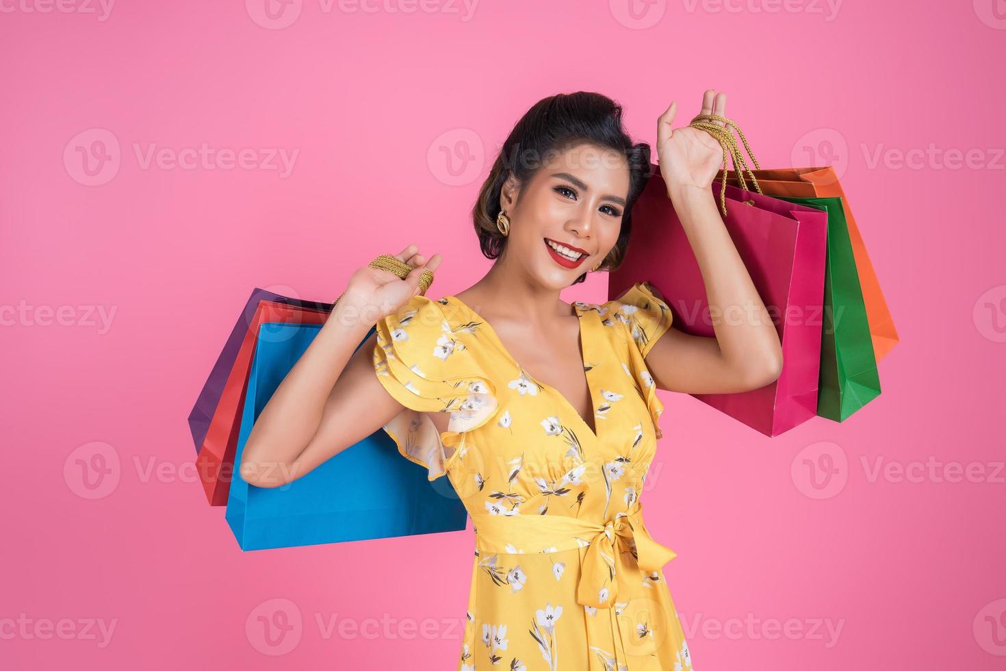 Beautiful Asian woman holding colored shopping bags photo