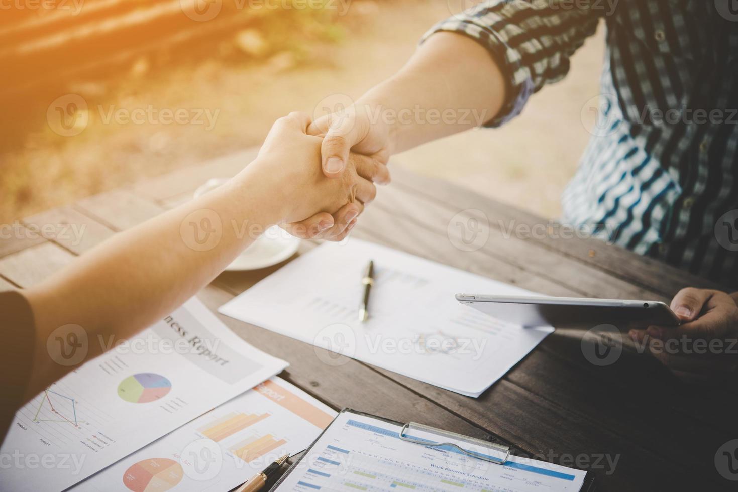 primer plano, de, dos, hombres de negocios, dándose la mano, mientras, sentado, en, el, lugar de trabajo foto