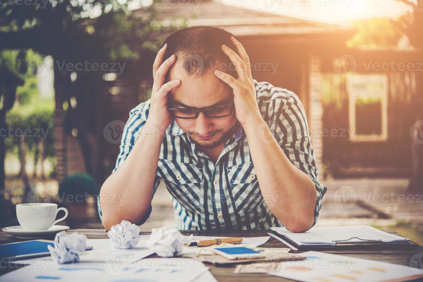 Stressed businessman with papers and charts sitting at table at home photo