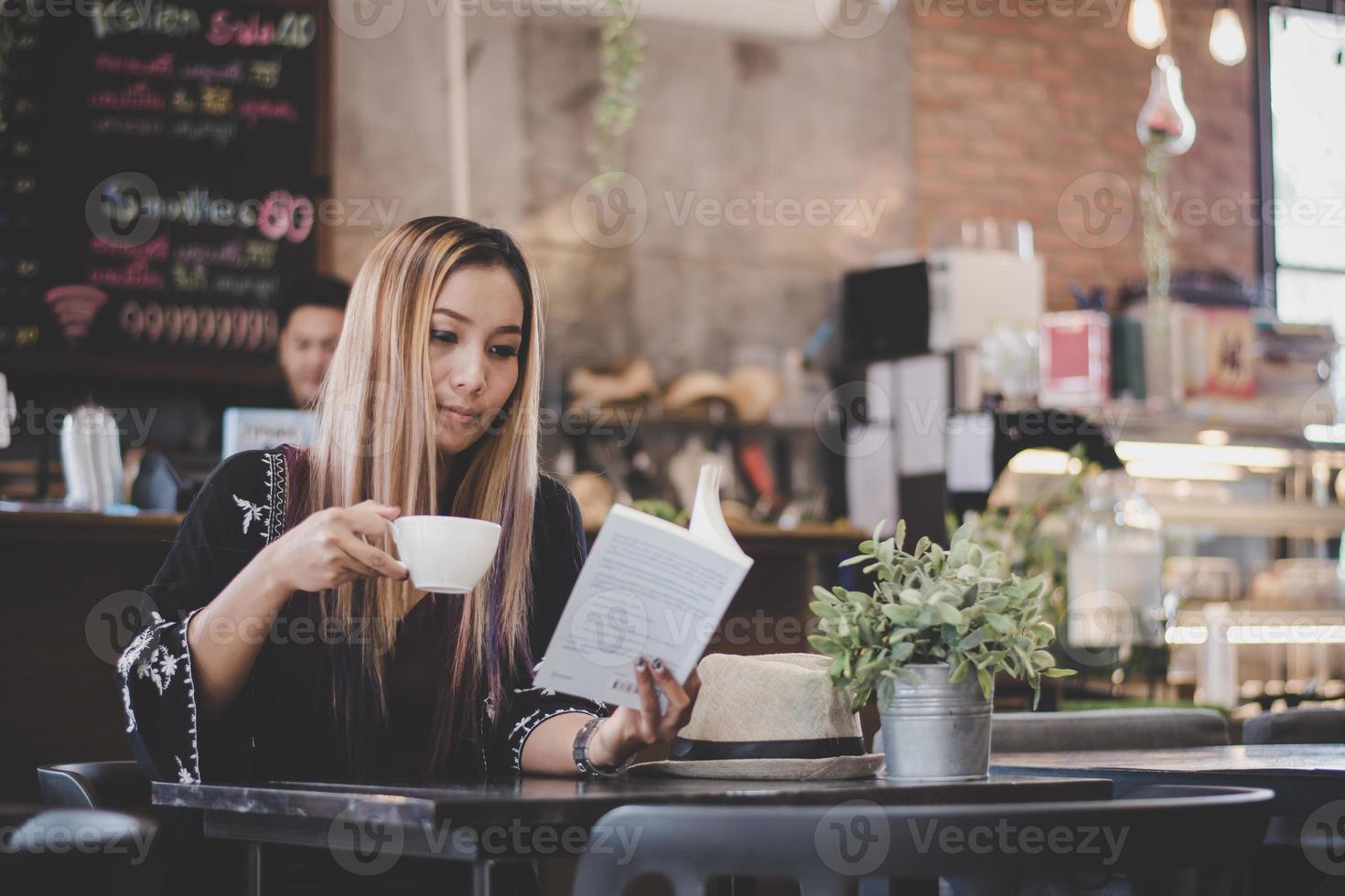 Feliz mujer de negocios leyendo un libro mientras se relaja en el café foto