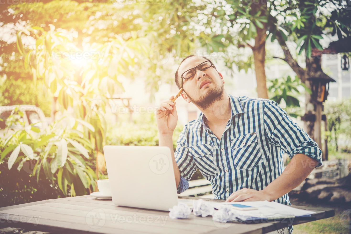 Businessman is thinking about something with pencil on head while working at home photo