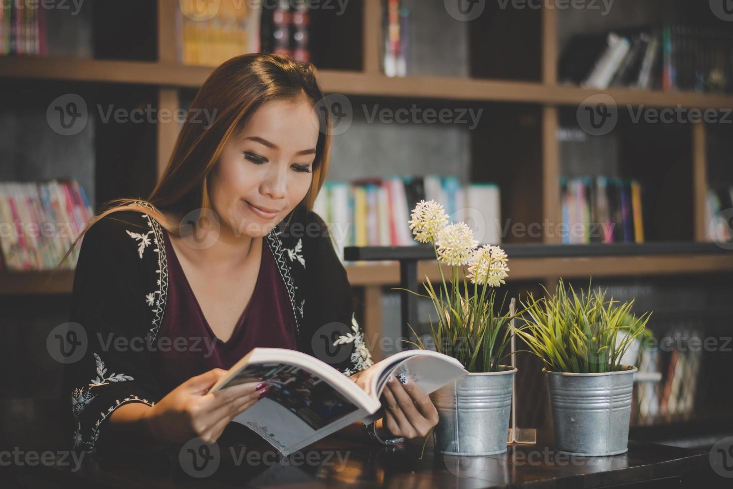 Feliz mujer de negocios leyendo un libro mientras se relaja en el café foto