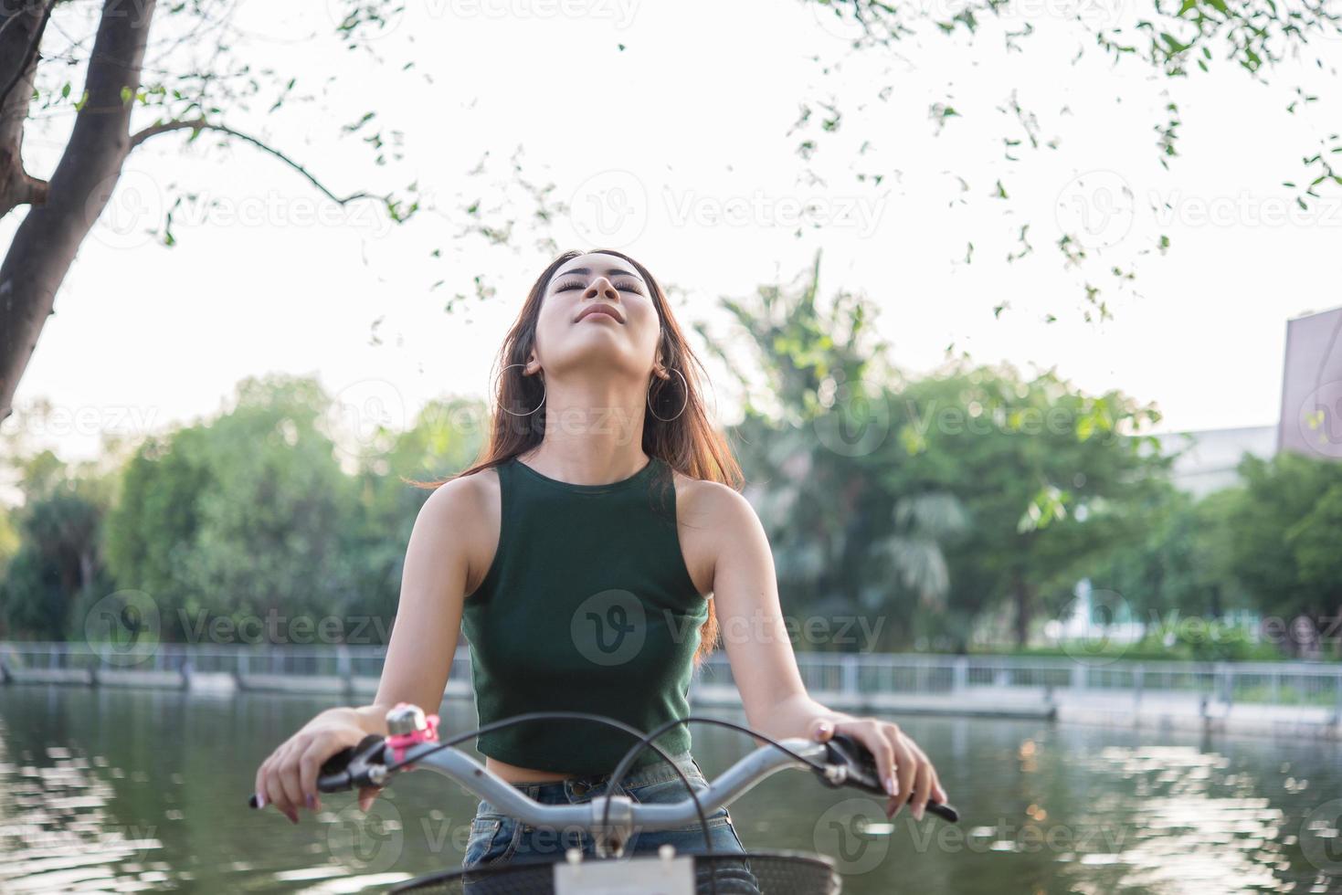 Hermosa joven montando bicicleta en el parque verde foto