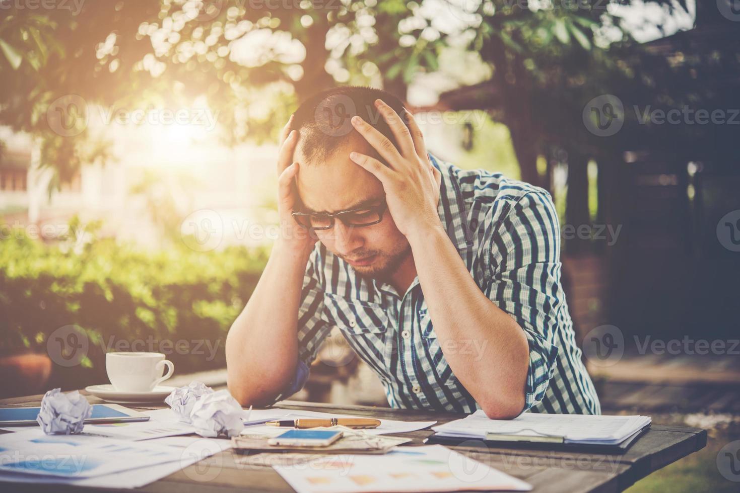 Stressed businessman with papers and charts sitting at table at home photo