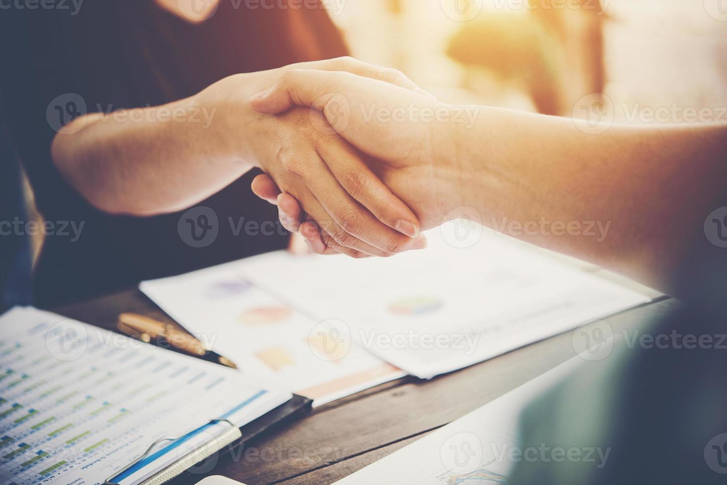 Close-up of two business people shaking hands while sitting at the working place photo