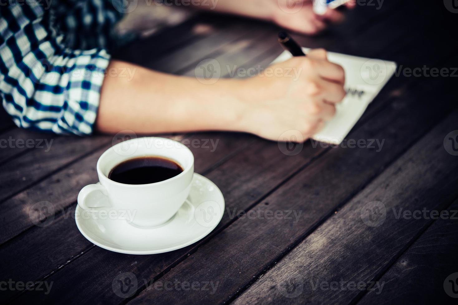 Close-up de empresario con smartphone mientras trabaja en la cafetería foto