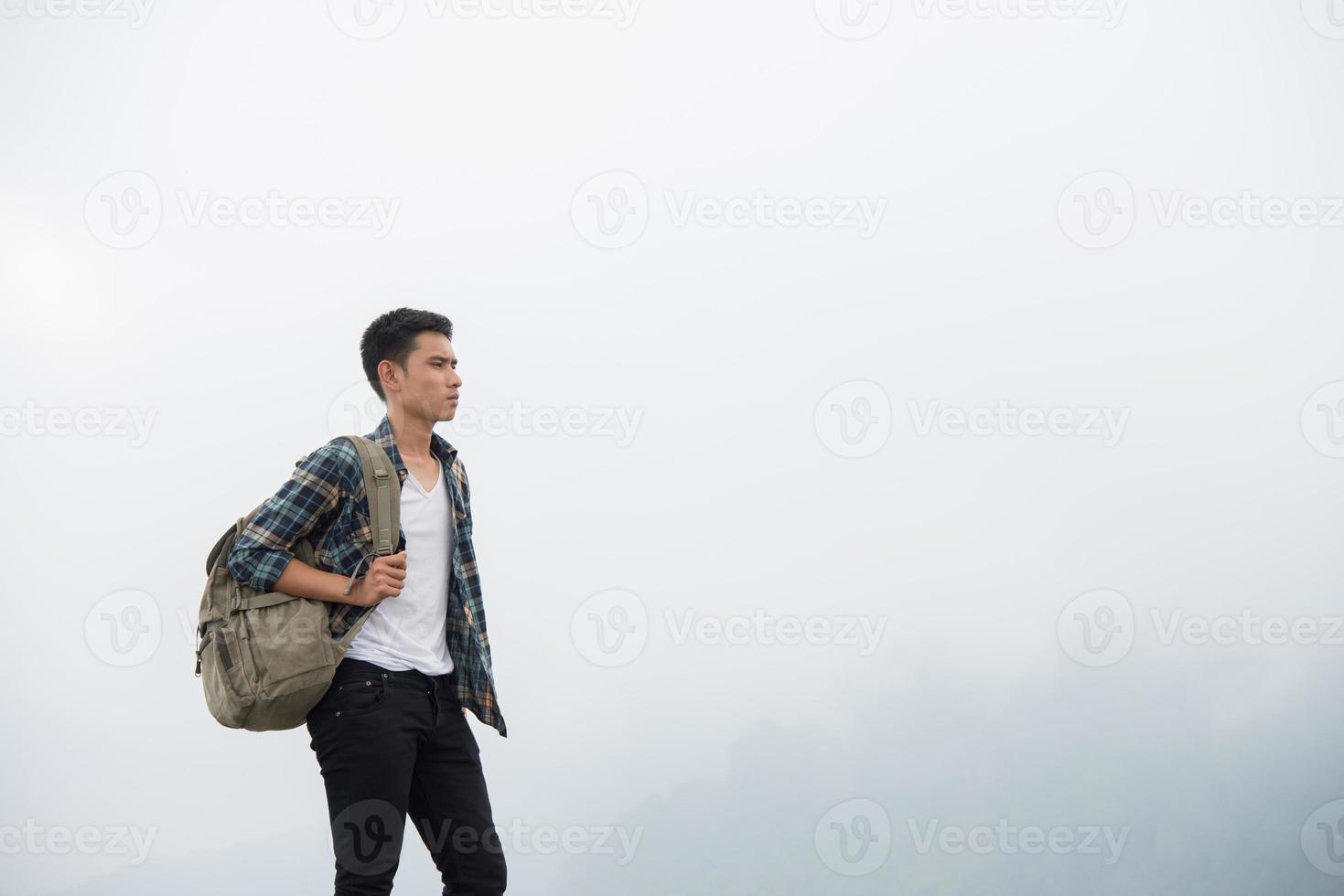 Hiker with backpack standing on top of a mountain and enjoying nature view photo