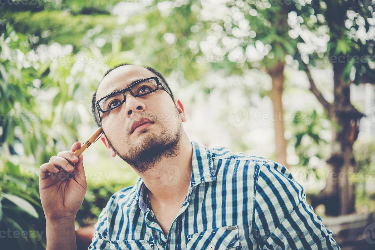 Businessman is thinking about something with pencil on head while working at home photo