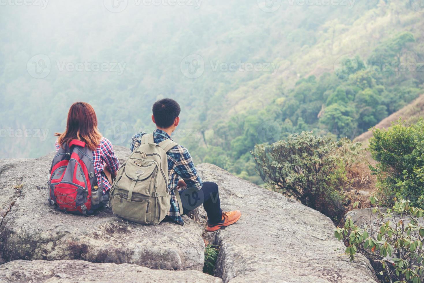 pareja joven disfruta de la vista en el pico de la montaña foto