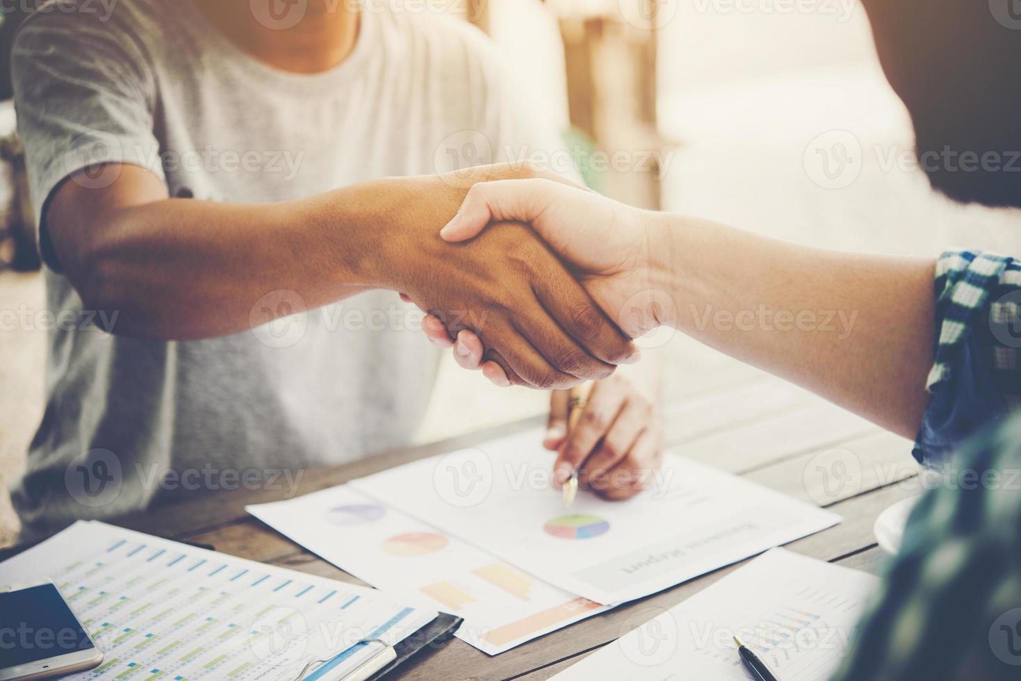 Close-up of two business people shaking hands while sitting at the working place photo