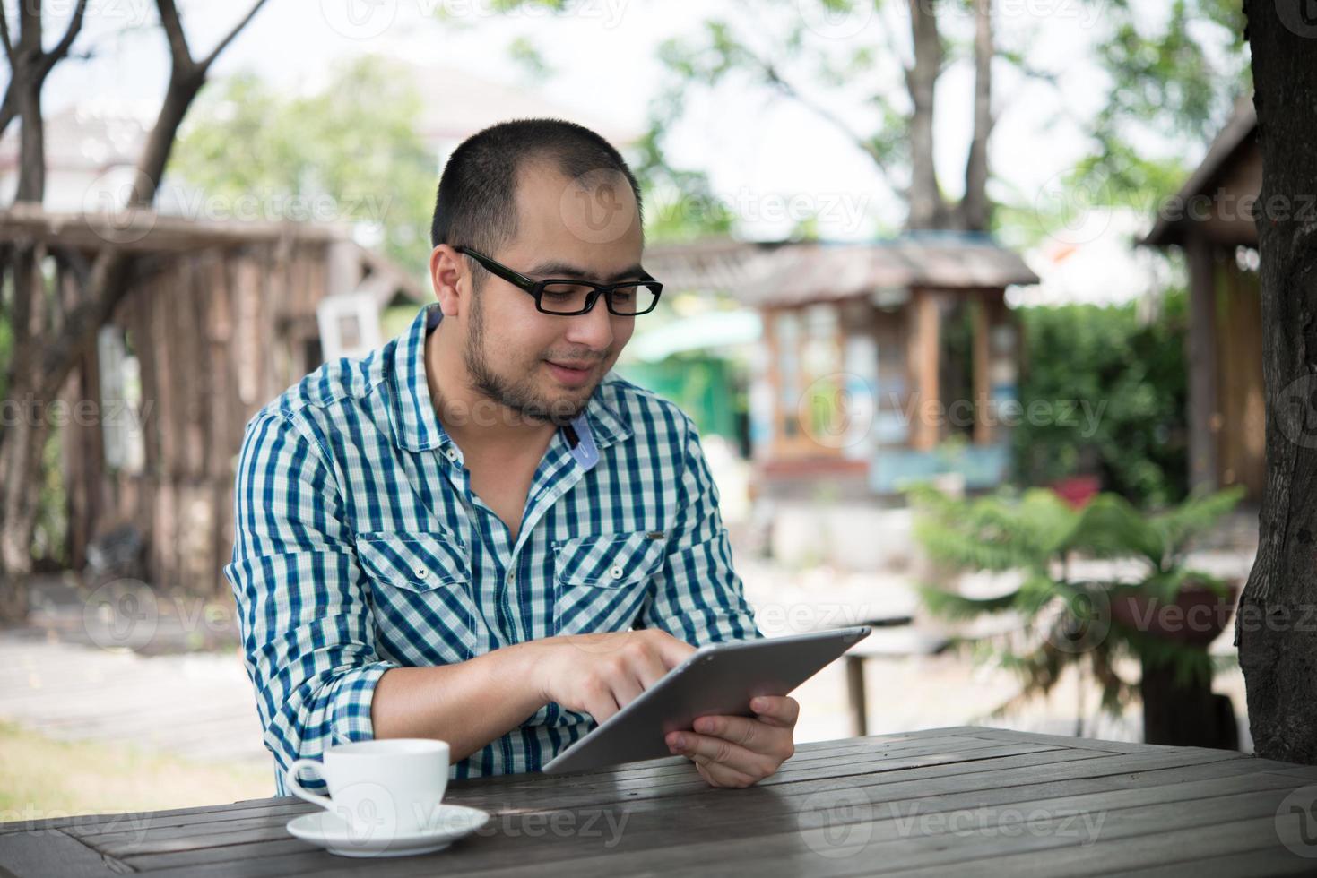 Businessman works on tablet while sitting at wooden table at home photo