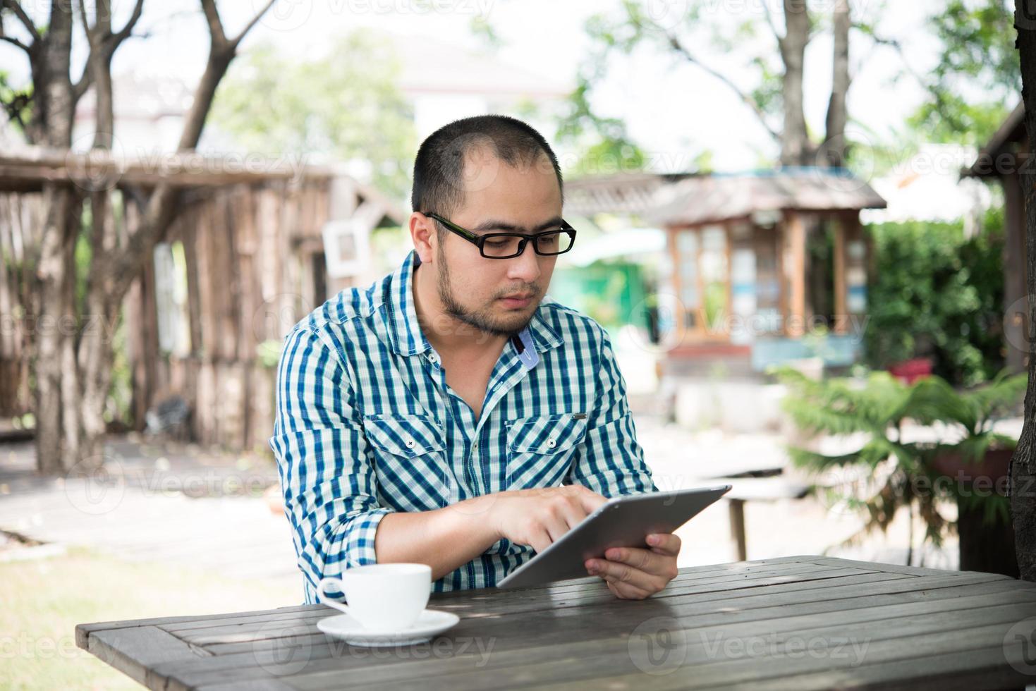 Businessman works on tablet while sitting at wooden table at home photo