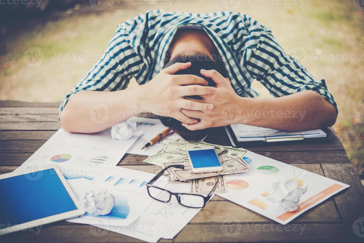 Hombre trabajador cansado durmiendo en el lugar de trabajo lleno de trabajo foto