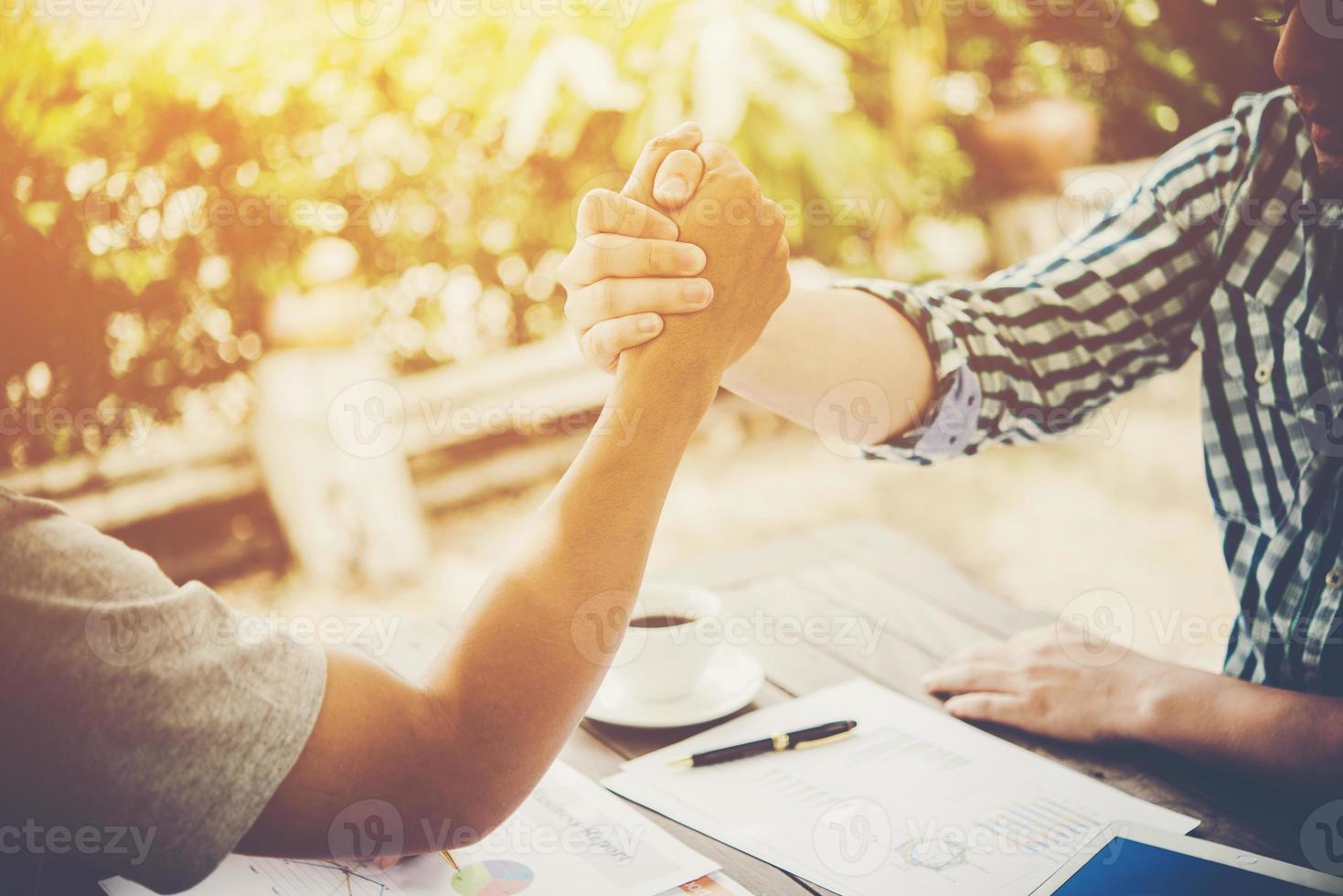 primer plano, de, dos, hombres de negocios, dándose la mano, mientras, sentado, en, el, lugar de trabajo foto