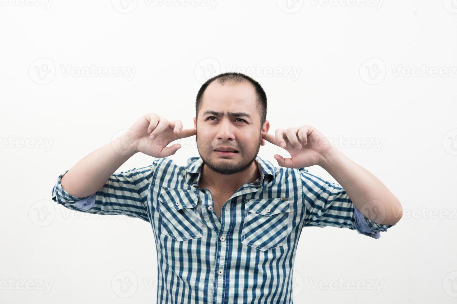 Portrait of young unhappy, stressed man covering his ears photo