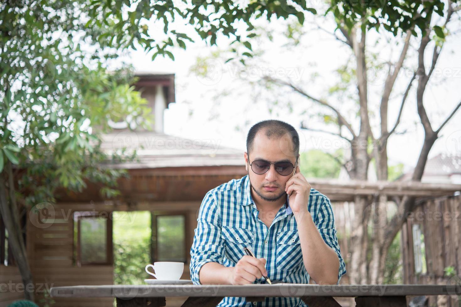 Young businessman using smartphone while working in the home garden photo