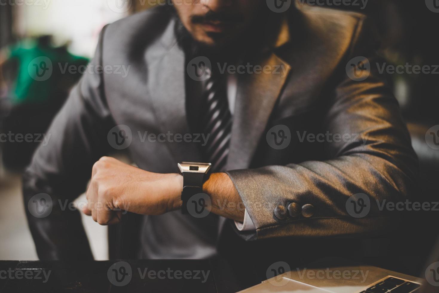 Close-up of businessman's hand looking at hand watch photo