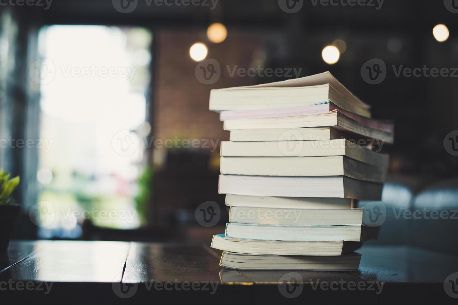 Piles of books on table over blurred library background photo