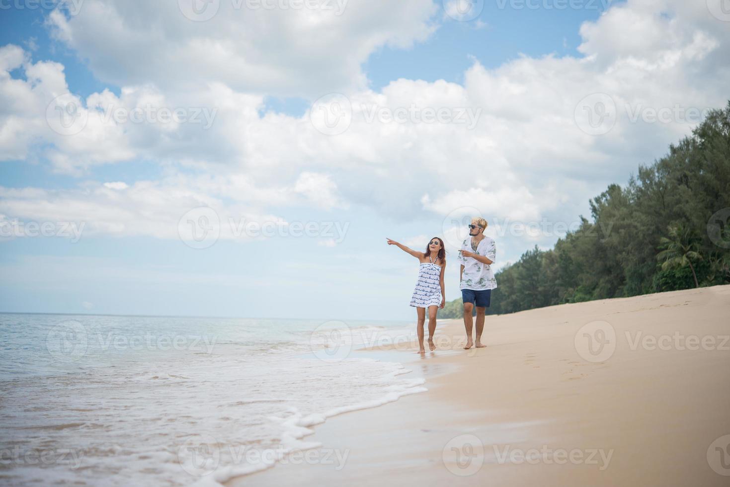 Young happy couple walking on beach smiling photo