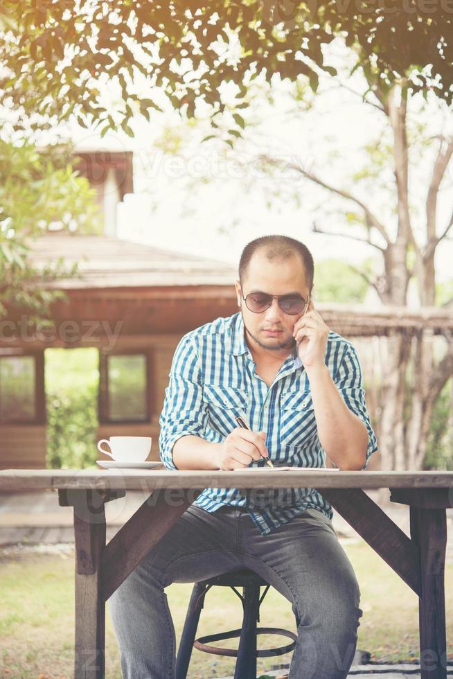 Young businessman using smartphone while working in the home garden photo