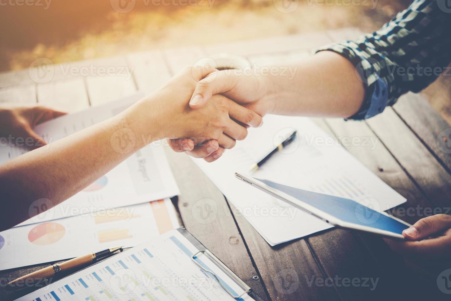 Close-up of two business people shaking hands while sitting at the working place photo