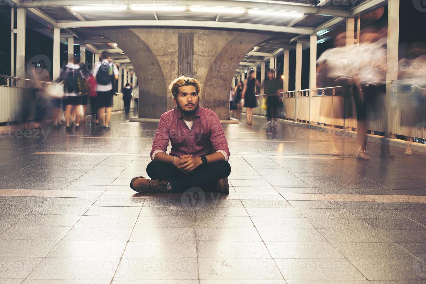 Hombre barbudo hipster sentado en el suelo mientras viaja de noche foto