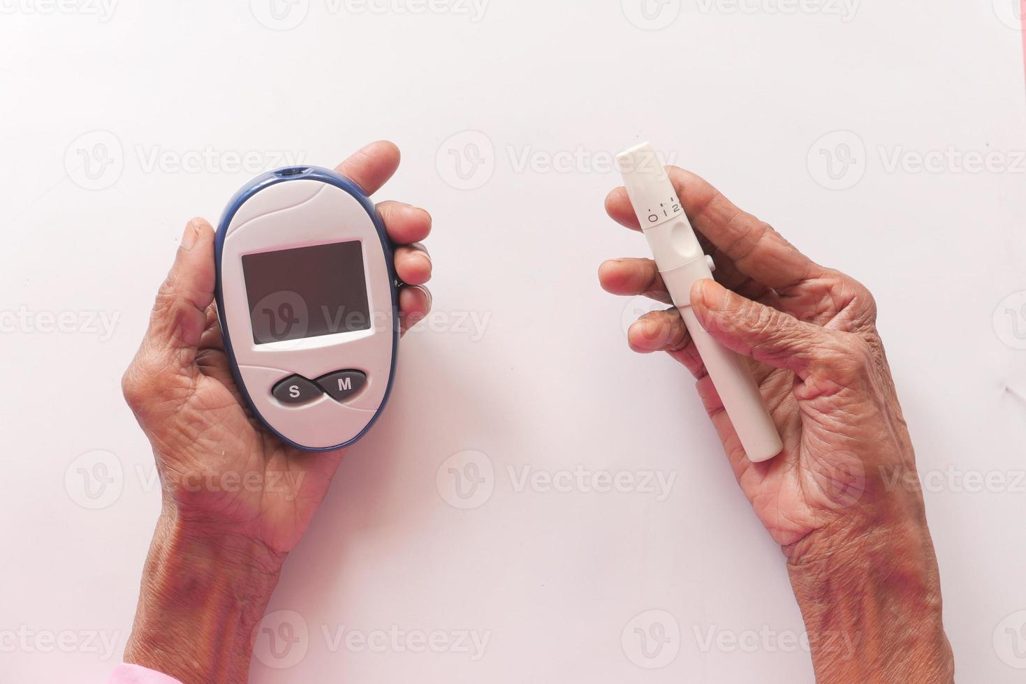 Las mujeres mayores diabéticas midiendo un nivel de glucosa en casa foto