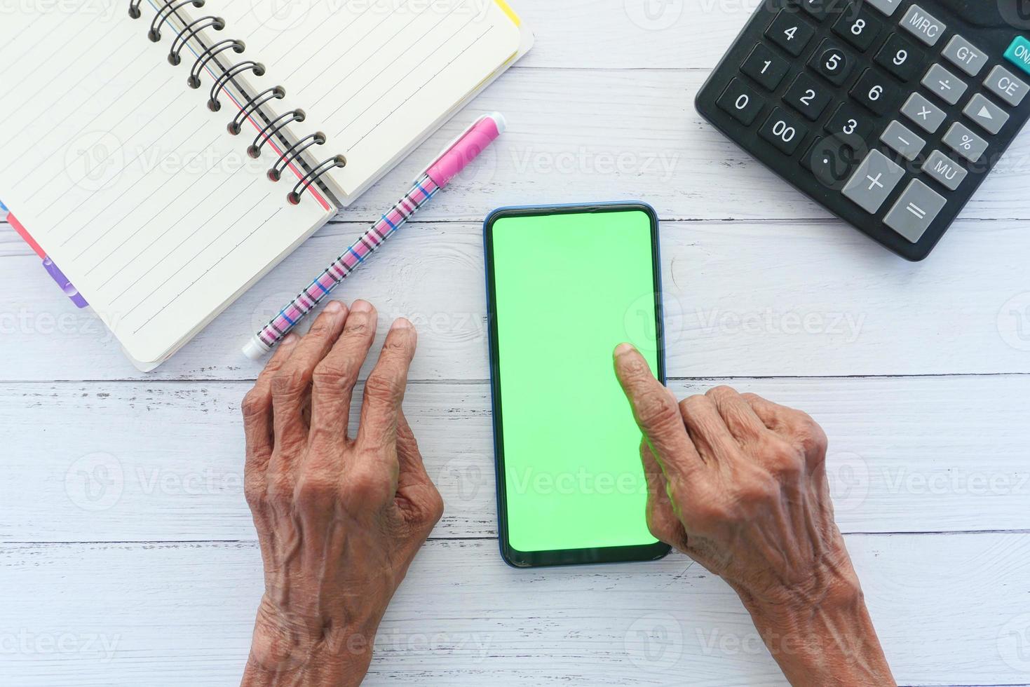 Old woman using a smart phone on a desk top photo