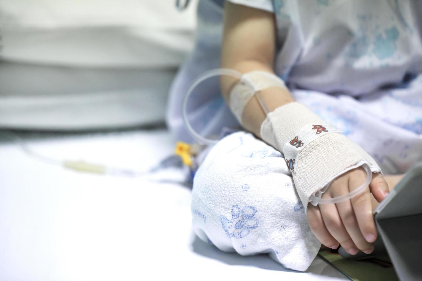 Sick child on a receiving a saline solution in hospital photo