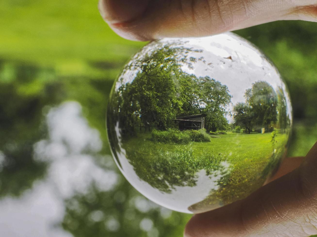 A shed seen through a glass ball held by hand photo