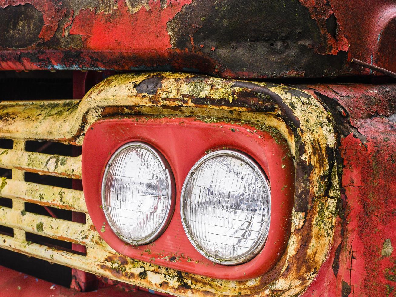 Detalle de los faros de un oxidado camión rojo y amarillo foto