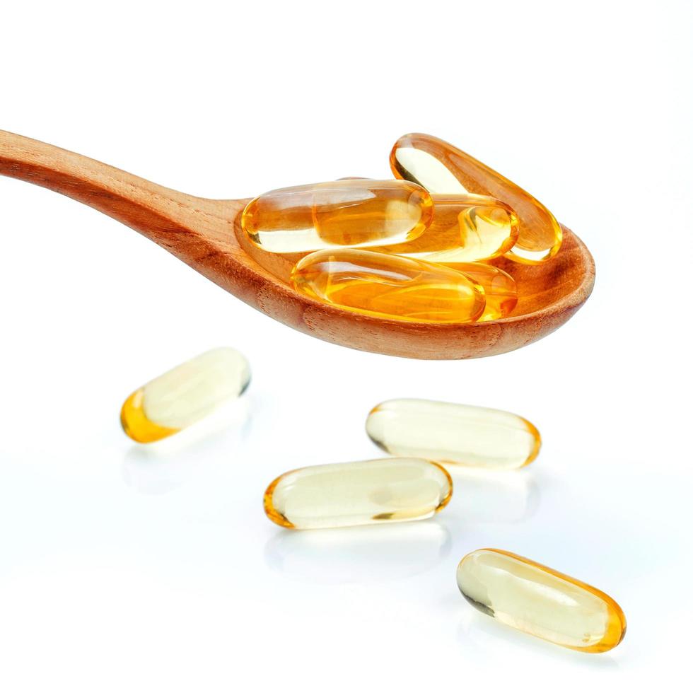 Fish oil pills in a spoon on white background photo