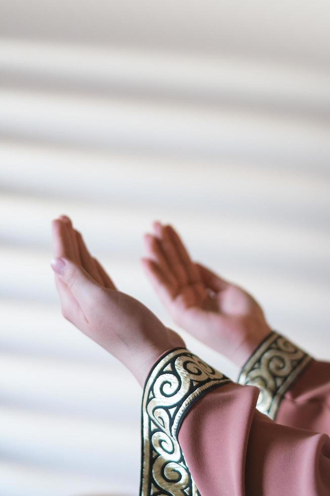 Hands of a Muslim or Islamic woman gesturing while praying at home photo