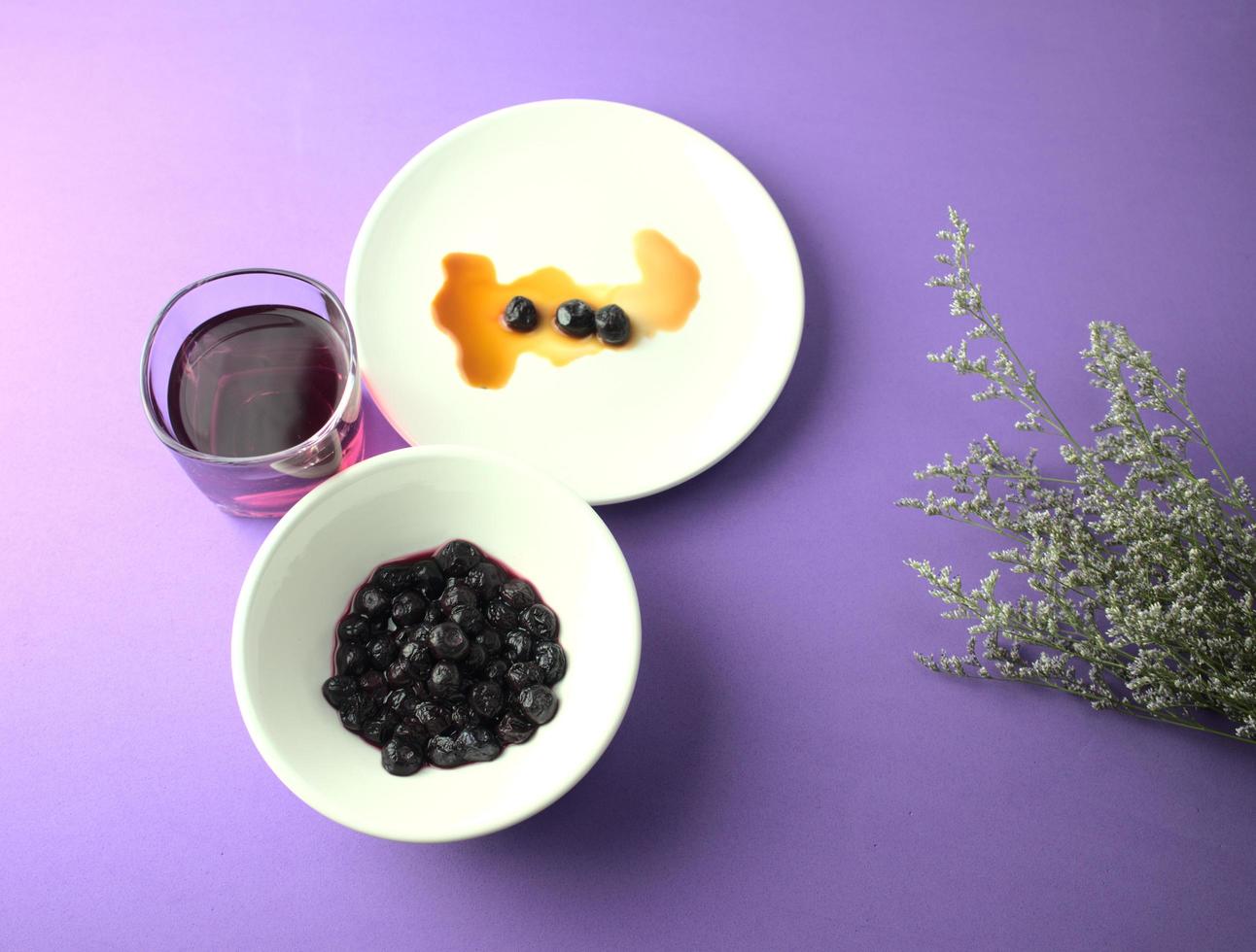 Blueberries, pulp in syrup, and blueberry juice on a purple background photo