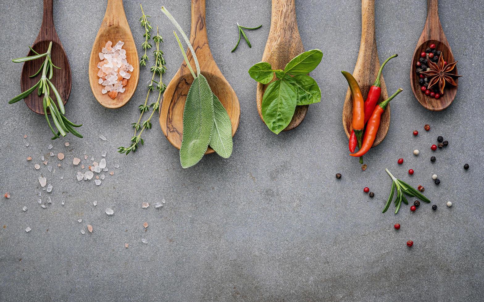 Herbs and spices in wooden spoons on a gray background photo