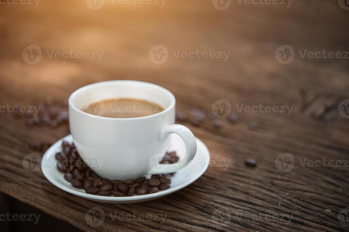 Taza de café y granos de café en la mesa de madera foto