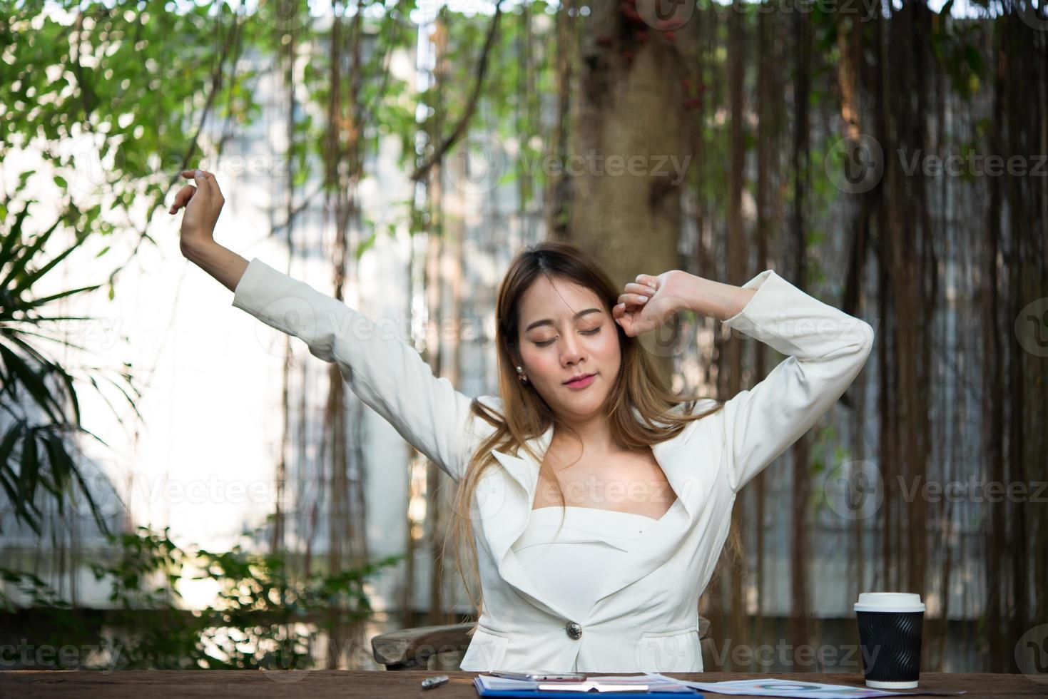 Young businesswoman stretching herself and yawning at workplace photo