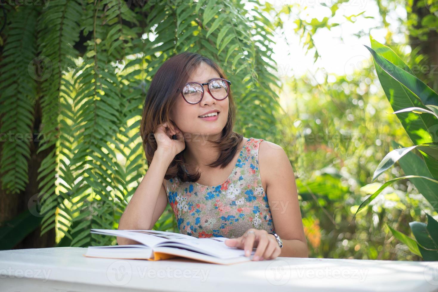 Young hipster woman reading books in home garden with nature photo