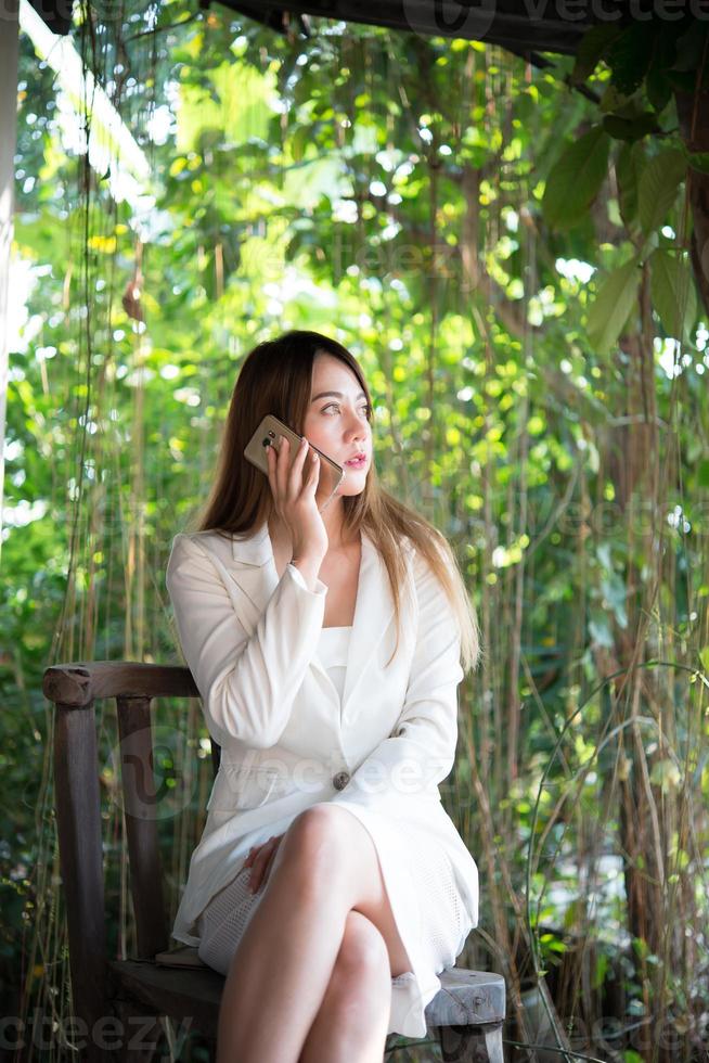 Businesswoman talking on the mobile phone and smiling while sitting in home garden photo