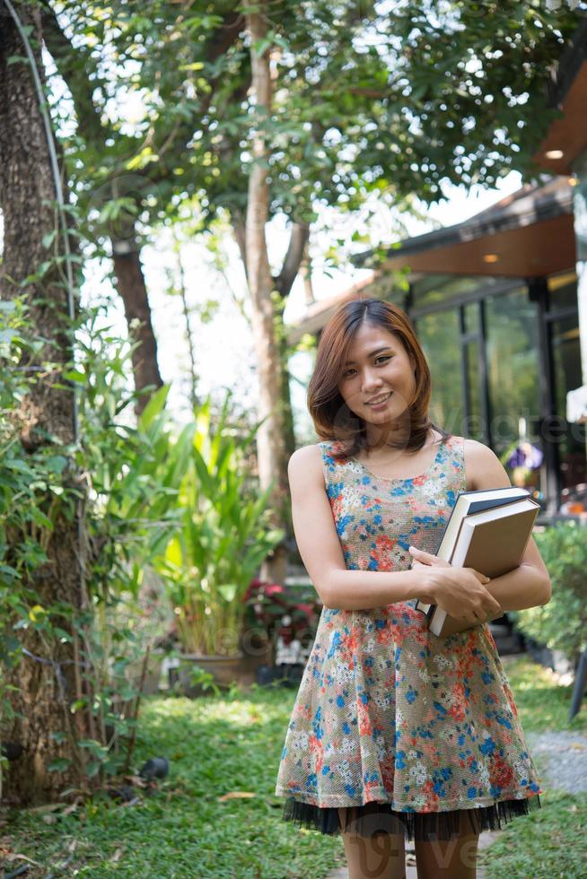 Feliz joven de pie y sosteniendo cuadernos en el jardín de su casa foto