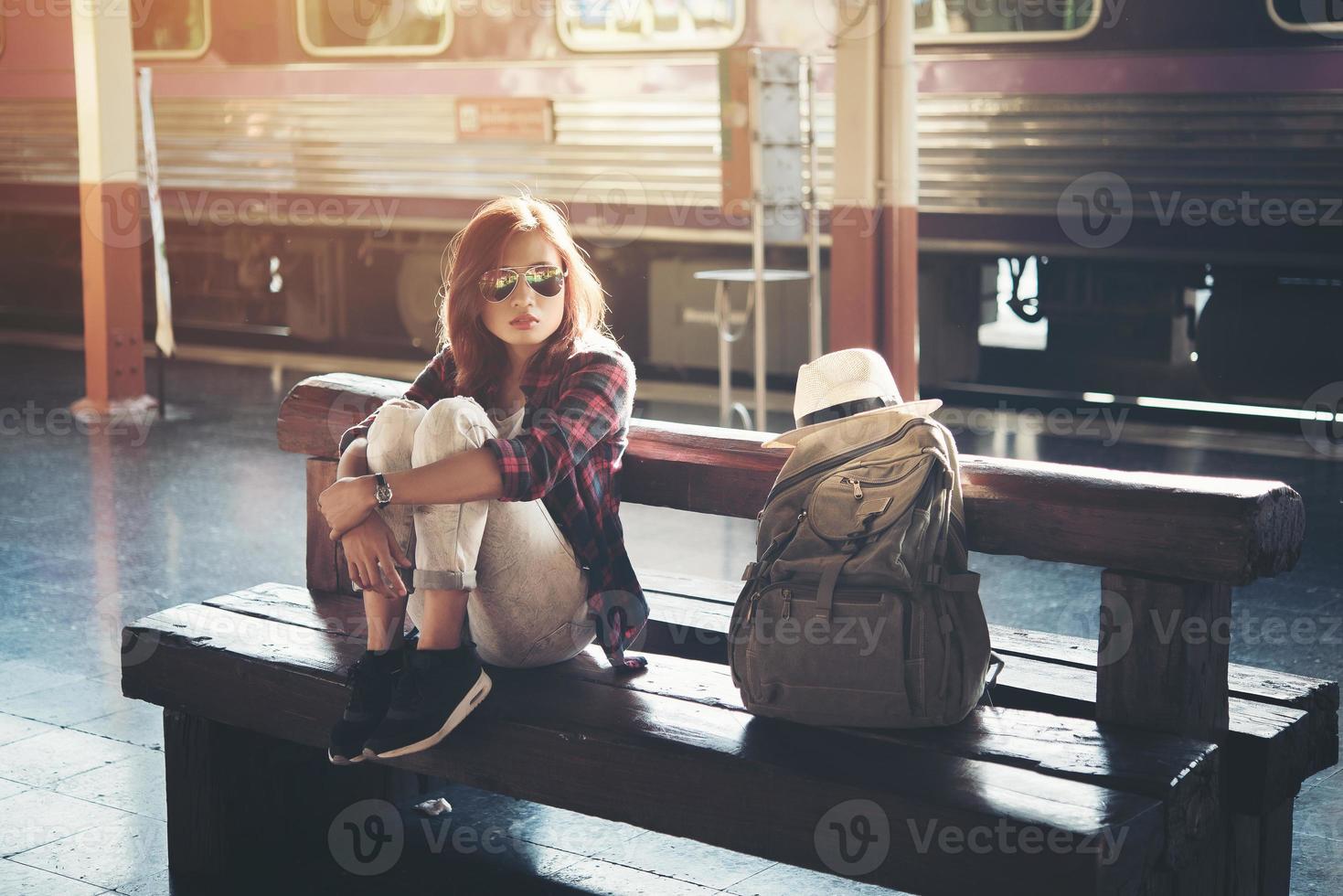 mujer inconformista mochilero sentado en la estación de tren foto