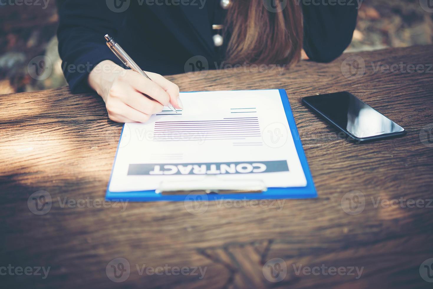 Mujer de negocios feliz firmando un documento en el escritorio trabajando en casa foto