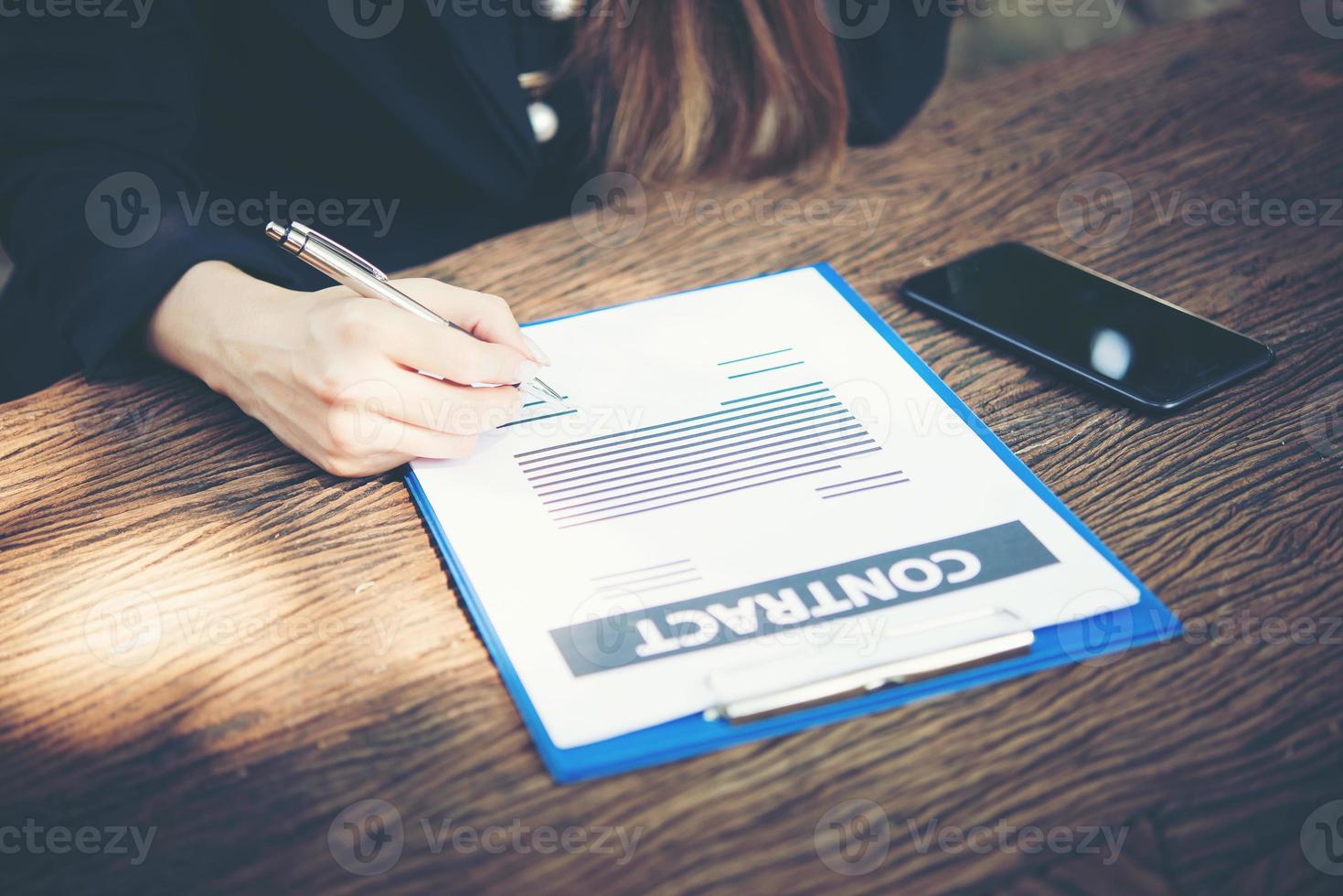 Happy business woman signing a document at desk working at home photo