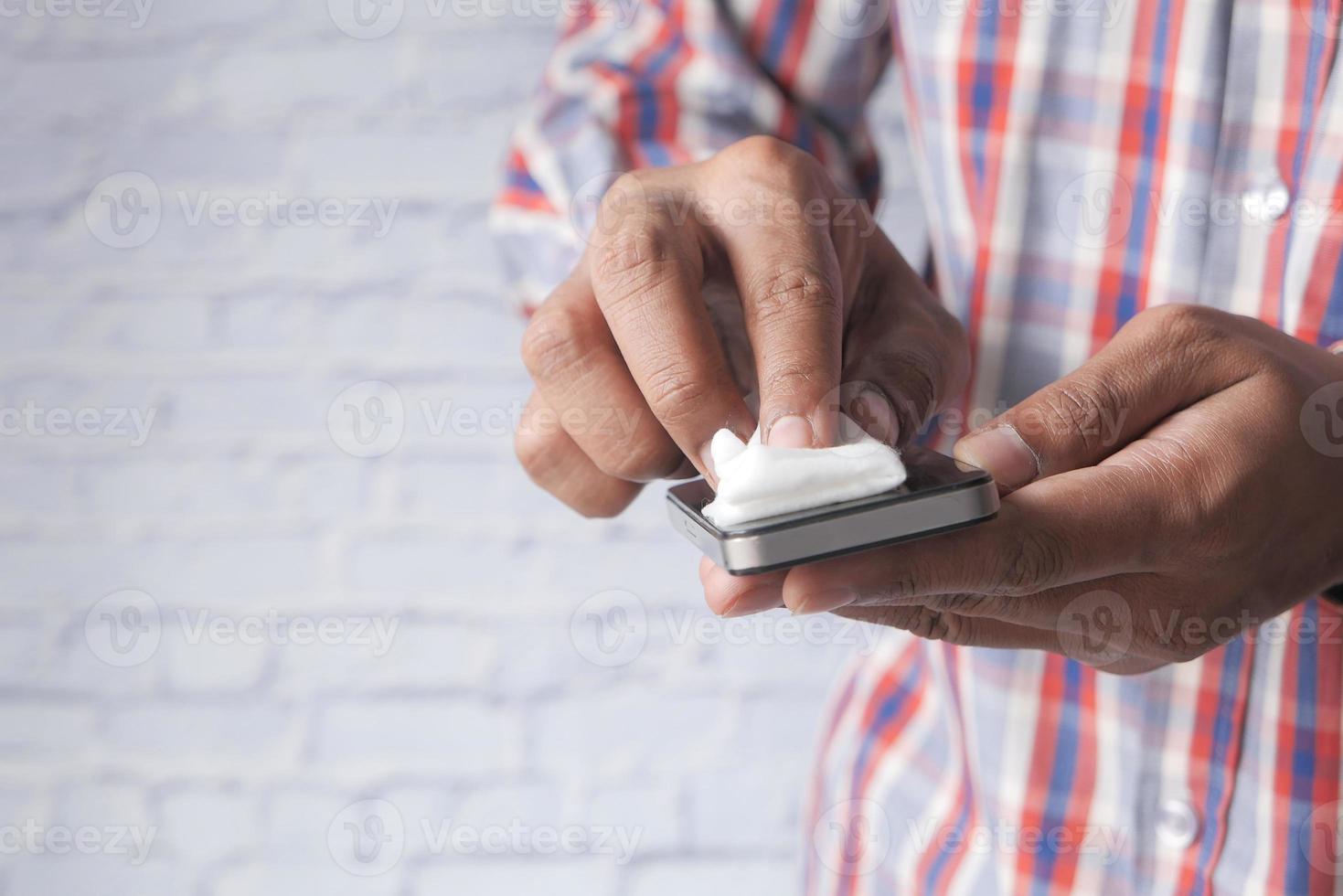 hombre limpiando la pantalla de un teléfono móvil foto